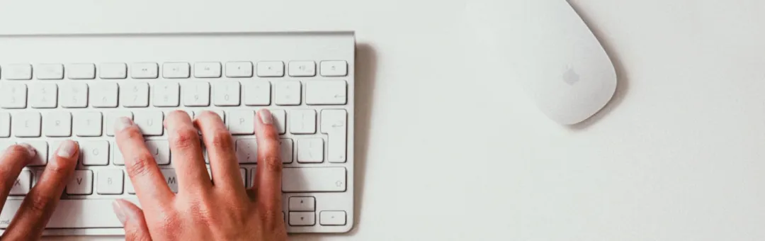 Apple-style keyboard and mouse with hand using them, showcasing sleek design and functionality